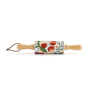 Top down view of a mini rolling pin with cherry design on the surface. A loop of black cord is threaded through a hole in the handle.on the left.