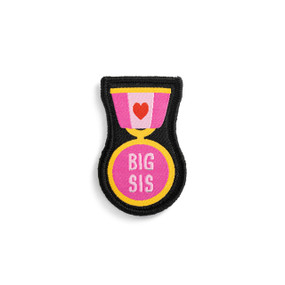 Front view of a badge. The badge is a pink and white medal on a ribbon pin, with a heart on the ribbon. The medal reads "Big Sis". The badge can be attached to a Just Add Heart Bear.