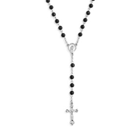 Detail view of the centerpiece and pendant of a silver rosary with black beads and a silver crucifix.