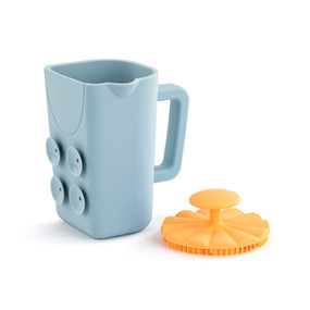 Front view of a blue bath cup and orange brush set. The cup is turned so the handle is on the right and suction cups are to the left. The brush is sitting to the right of the cup, bristle side down.