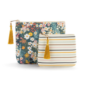Top down view of two zippered fabric bags. The small bag is in front and slightly to the right of the large bag. The small bag has narrow multicolored stripes on a white background. The large bag has a print small multicolored flowers and green leaves. The zipper pulls on top of the bags are to the left and have gold tassels attached.