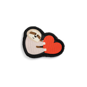 Front view of an irregularly shaped badge. The badge is a light brown sloth hanging on to the left side of a red heart. The badge can be attached to a Just Add Heart Bear.