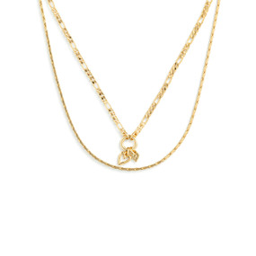 Top down view of a layered necklace of two gold chains, The smaller gold chain has a pendant of two heart charms on a small gold ring.