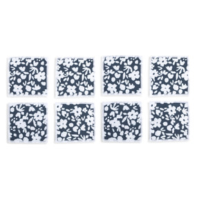 Top down view of four fabric napkins with white flowers on a navy blue background and white edging, The napkins are arranged in a 2x2 grid and tilted to the left.