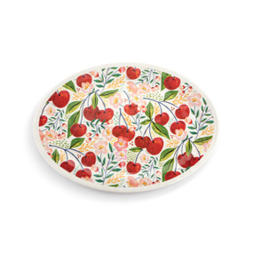 Top down view of a large oval melamine platter, decorated with a print of cherries and green leaves.
