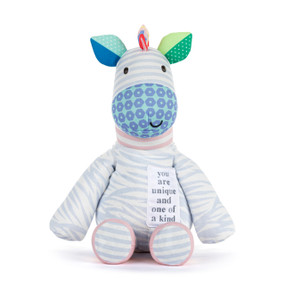 Front view of a plush zebra. The zebra's body is blue and white zebra stripes. A patch on the left side of the chest reads "You are unique and one of a kind". The neck is pink and white stripes. The face is purple and white stripes, and the nose has a blue and white pattern. The left ear is light and dark green, the right ear is light and dark blue.