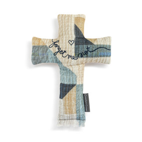 Top down view of a blue, tan and cream cross shaped pillow. The words "forget me not" and a small heart are embroidered in script at the center of the crossbar.