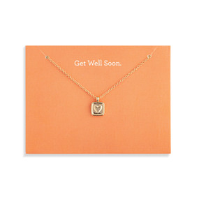 Top down view of a gold necklace and a square gold charm with a heart at its center attached to an orange card. "Get well soon" is printed at the top of the card above the necklace.