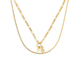 Top down view of a layered necklace of two gold chains. The smaller gold chain has a pendant of a heart charm and a cross charm on a small gold ring.