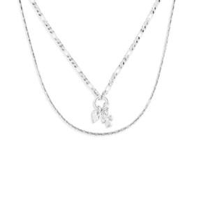 Top down view of a layered necklace of two silver chains. The smaller silver chain has a pendant of a heart charm and a cross charm on a small silver ring.