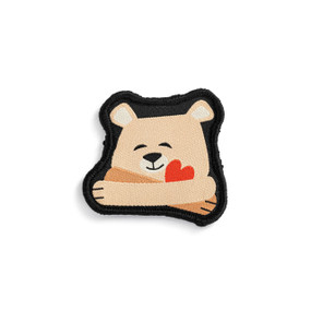 Front view of an irregularly shaped badge. The badge a light brown bear with its arms wrapped around a red heart in a hug. The badge can be attached to a Just Add Heart Bear.
