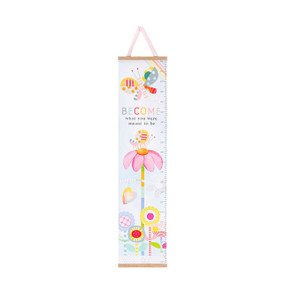 Front view of a canvas growth chart that can be hung on a wall. The canvas is printed with several multicolored flowers at different heights at the bottom, and a colorful butterfly at the top. The phrase "Become what you were meant to be" is printed between the tallest flower and the butterfly. A ruler is printed on the right side of the canvas. A sheer pink ribbon is attached to a wood bar at the top for hanging. A wood bar at the bottom keeps the chart sturdy and hanging straight.