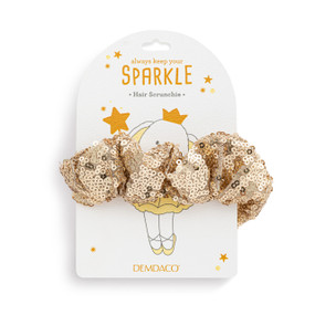 Top down view of a gold sequined hair scrunchie on a white packaging card.