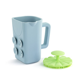 Front view of a blue bath cup and green brush set. The cup is turned so the handle is on the right and suction cups are to the left. The brush is sitting to the right of the cup, bristle side down.
