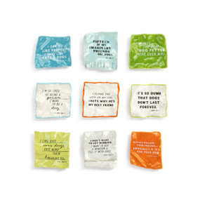 Top down view of an assortment of nine square ceramic magnets, arranged in a three-by-three grid. Each magnet resembles a smoothed-out piece of crumpled notepaper and has a different funny quote from a young child about pets.