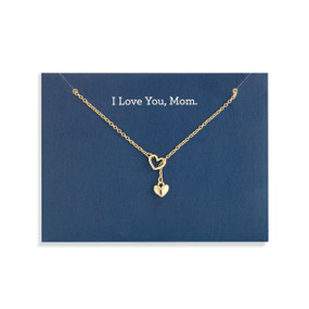 Top down view of a gold necklace with a gold heart charm attached to a dark blue card. "I love you, Mom" is printed at the top of the card above the necklace.