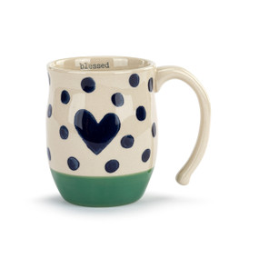 Image of the front of a white ceramic mug with a solid green base and decorated with dark blue polka dots. There is a large dark blue heart at the center. The word "blessed" is printed in typeface on the mug's interior. The mug's handle is to the right.