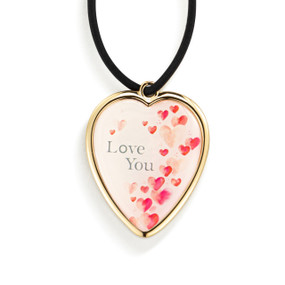 Top down view of the front of a heart shaped gift tag for a wine bottle, strung with a black cord. The heart has a design on a pale pink background featuring a shower of red hearts on the right side and the words "love you" in the upper left.