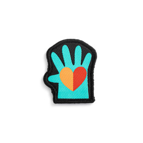Front view of an irregularly shaped badge. The badge is a green hand with a red and orange heart in the palm. The badge can be attached to a Just Add Heart Bear.