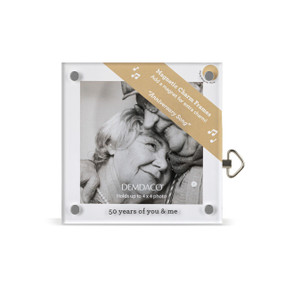 Top down view of a square acrylic musical frame with magnets in each corner. "50 years of you & me" is printed at the bottom. A brown banner in the upper right corner indicates the music box plays "Anniversary Song"..