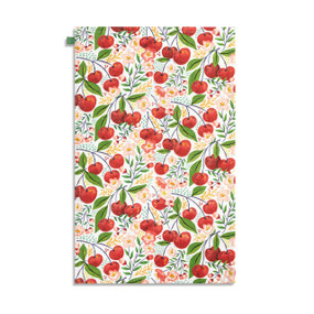 Top down view of the front side of a kitchen towel printed with cherries on stems and cherry flower blossoms with green and yellow leaves.
