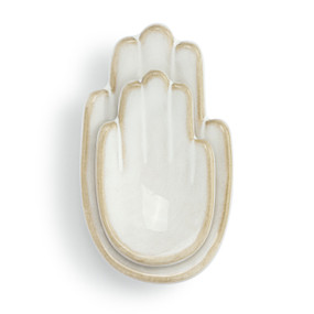 Top down view of a white ceramic trinket dish. The dish is two right hands, palm up, a smaller hand atop the larger.