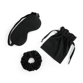 Top down view of a gift set containing a black eyemask, a black hair scrunchie and a black drawstring gift bag.
