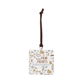 Front view of a square white ornament strung with a black cord for hanging. "Leave paw prints wherever you go" is printed at the center against a background of small illustrations of different breeds of cats and dogs.