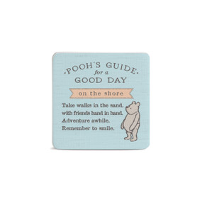 Front facing view of a light blue square magnet with an illustration of classic Winnie-the-Pooh in the lower right corner. "Pooh's Guide for a good day at the shore. Talke walks in the sand with friends hand in hand. Adventure awhile. Remember to smile." is printed across the middle.