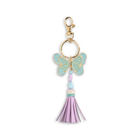 Front view of an blue and gold butterfly bag charm with a purple tassel. The charm is attached to a gold ring which hangs from a lobster clasp.