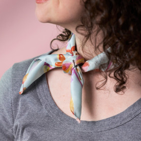 A woman wears a light green bandana scarf tied around her neck.