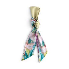 Top down view of a skinny tie style scarf for bags. The scarf is displayed doubled over and tied with a knot at the center. One side of the scarf has a floral print with green accents. The other side is solid light green.