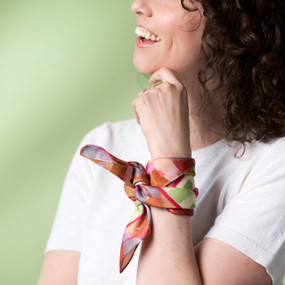 A woman wears a pink floral printed bandana scarf tied around her left wrist.