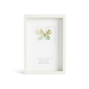 Front facing view of a white rectangular shadow box. At the top is a sculpted green and white butterfly with gold and brown markings. "The wind knows where to go. Spread your wings, trust your heart, and let it carry you." is printed in typeface centered at the bottom.