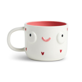 Front facing view of a white character mug with a red interior and red small red hearts along the rim and base. The mug's handle is to the left. The mug is named Hazel Busy Mom and has a smiling face on her front.