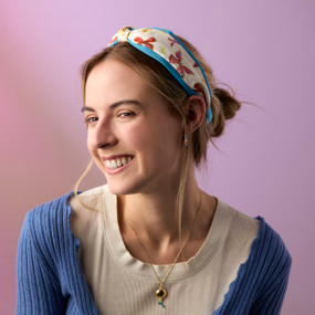 A young woman wears a blue and white print fabric headband with a knot slightly off center at the top.