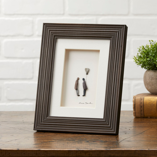 Dark wooden photo frame with two pebble figurines and a balloon inside