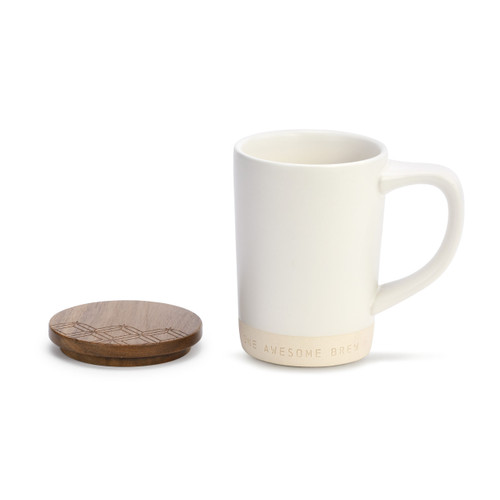 A white and ivory coffee mug that reads "one awesome brew" with a wooden coaster.