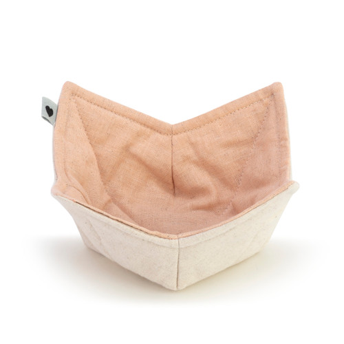 A front view of a bowl pot holder with a peach color fabric on the inside and a cream fabric on the outside.