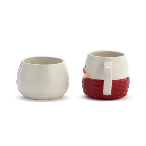 Side handle view of a white stoneware set of a bowl and mug shaped like a snowman wrapped in a red scarf. There is a red patch on the bowl that says "Stay Cozy".