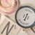 Two cake trays placed on top of a white hardwood surface. Placed beside a banner with the word "One". One plate is pink, while the other is gray and white, and reads "Hooray! It's my big day!"