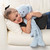Close up view of a young girl laying on an off white couch and hugging a light blue puppy blankie.