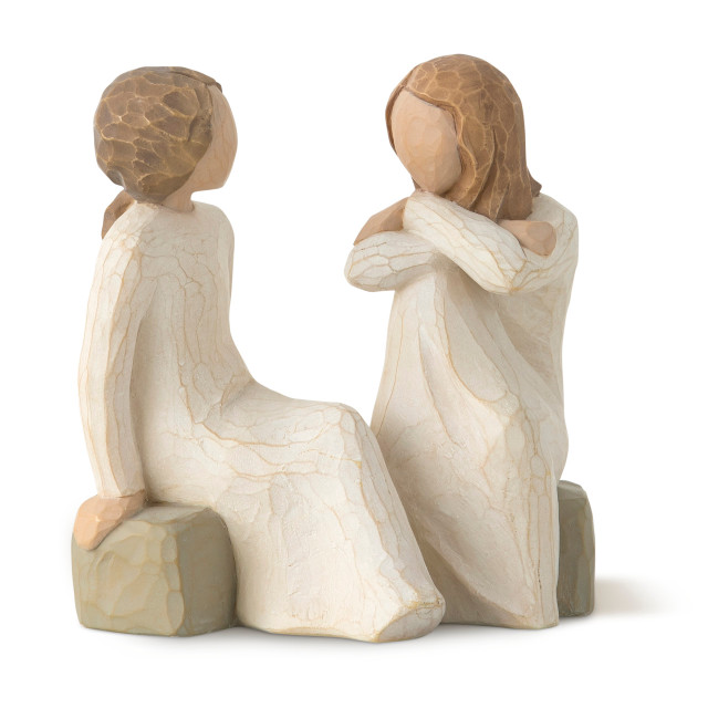 Front view of two female figures in cream dresses seated on gray rock, facing each other