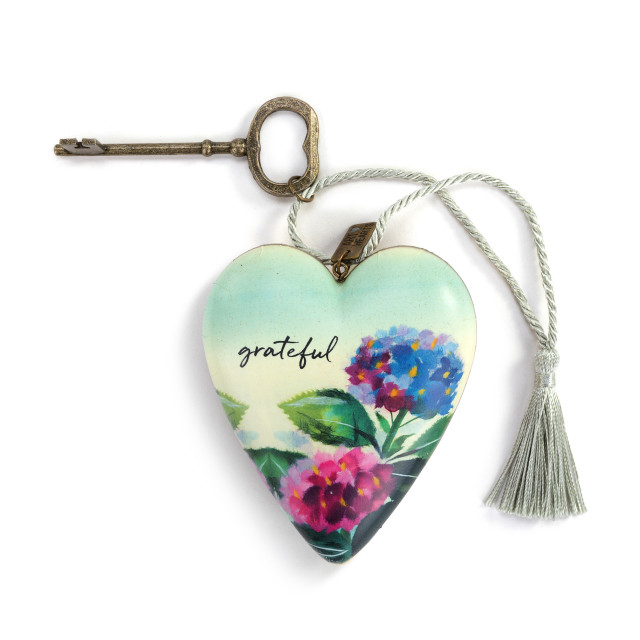A heart shaped sculpture with a gold key and silver tassel with artwork created by ArtLifting artist Midori. The image is a blue and red hydrangea.