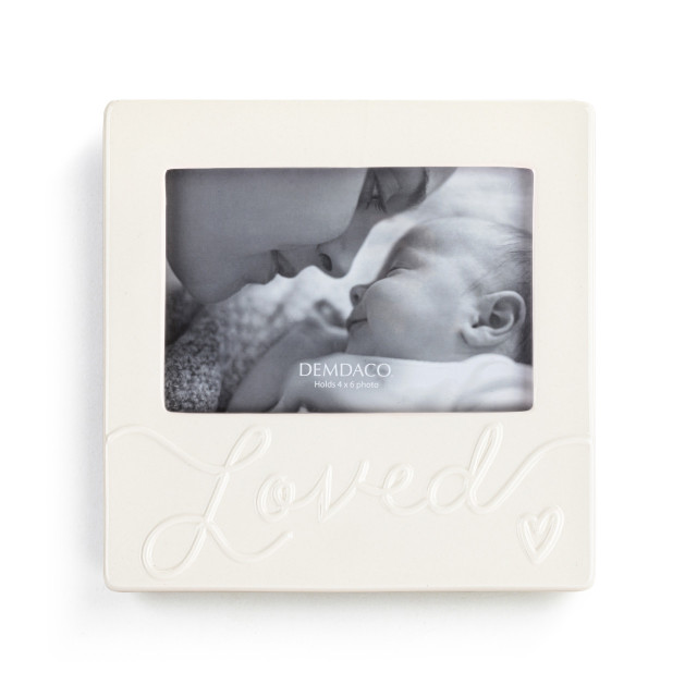 A cream ceramic photo frame holding a 4x6 photo that has the word 