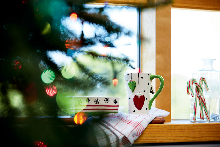 Christmas mug sitting on a widow sill next to a Christmas tree.