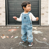 Baby boy wearing Crayola® Never Run with Scissors Soft Soles in Black, in front of the garage drawing with chalks