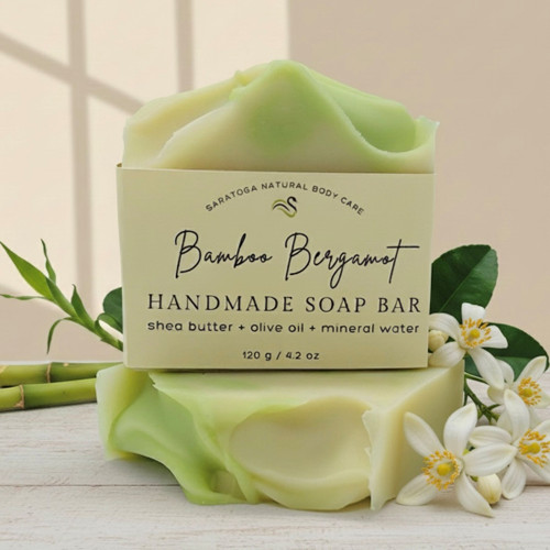 Close-up of Bamboo Bergamot handmade soap bar with shea butter and olive oil, featuring soft green marbling and floral accents for a fresh, spa-like presentation.