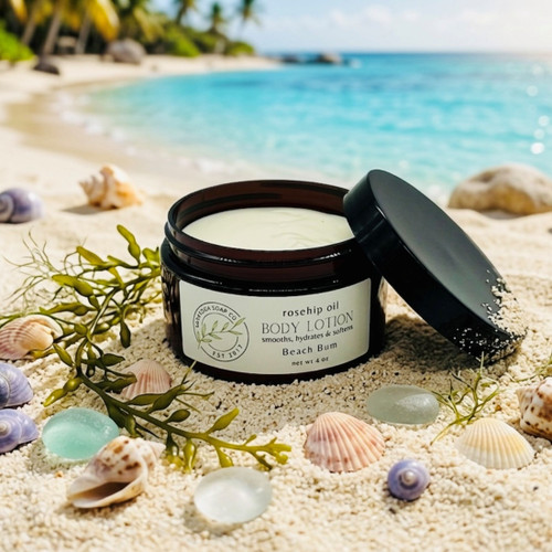 Beach Bum body lotion styled on a tropical beach with seashells and sea glass, summer scented rosehip oil body lotion, nourishing hydrating skincare