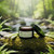 An open jar of lemongrass body lotion is placed on a mossy log. Several stalks of lemongrass are arranged around the jar. The setting is a lush forest with a blurred stream and ferns in the background.